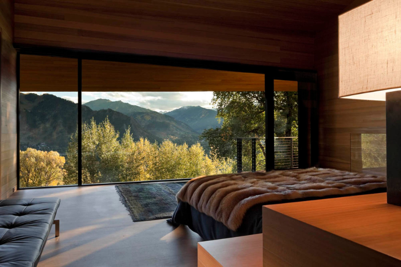 Peter Marino - Aspen Residence. Master bedroom with blue rug and a wooden floor.