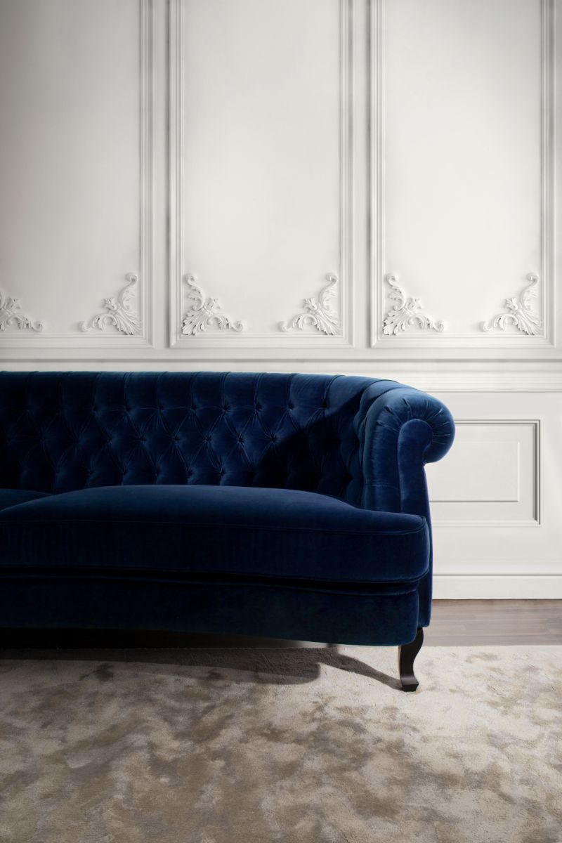 Living room with area rug in gray tones with blue velvet sofa