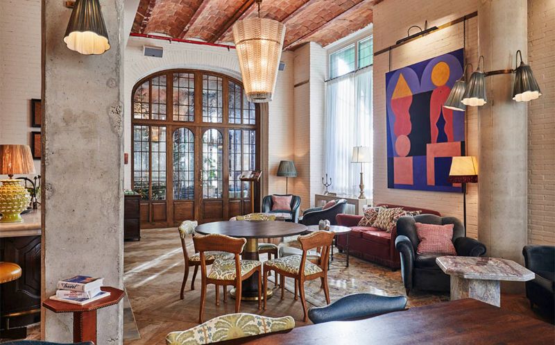 living room with sofas, black armchirs, wood dining tables, rug, geometric painting, lamps