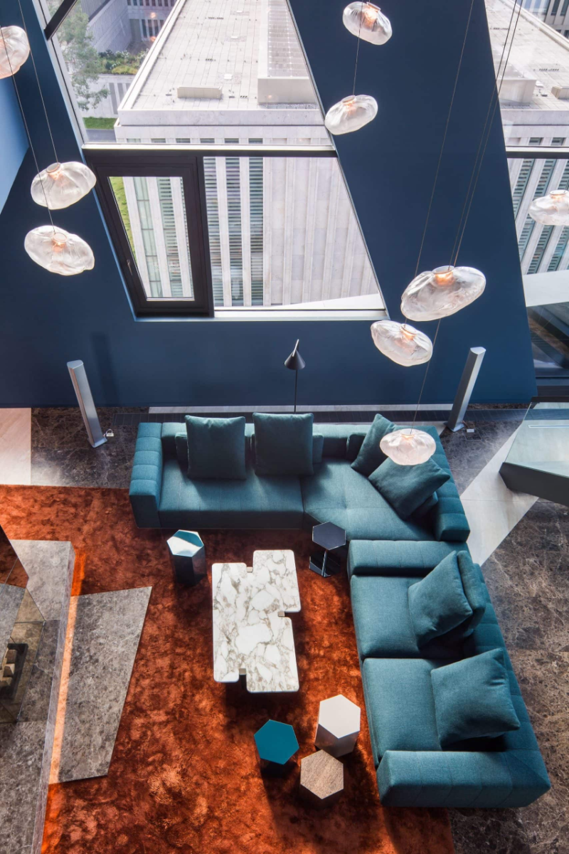 PENTHOUSE 105 living room with an orange modern rug designs, a blue couch, and some pendant lights