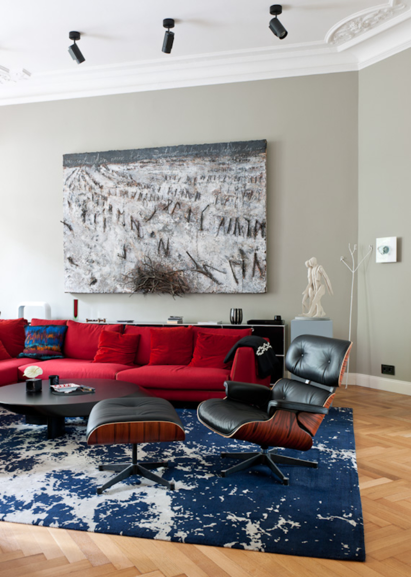 Gisbert Pöppler, The Art of Viewing living room with a blue rug, a classic reclainer chair and a red sofa.