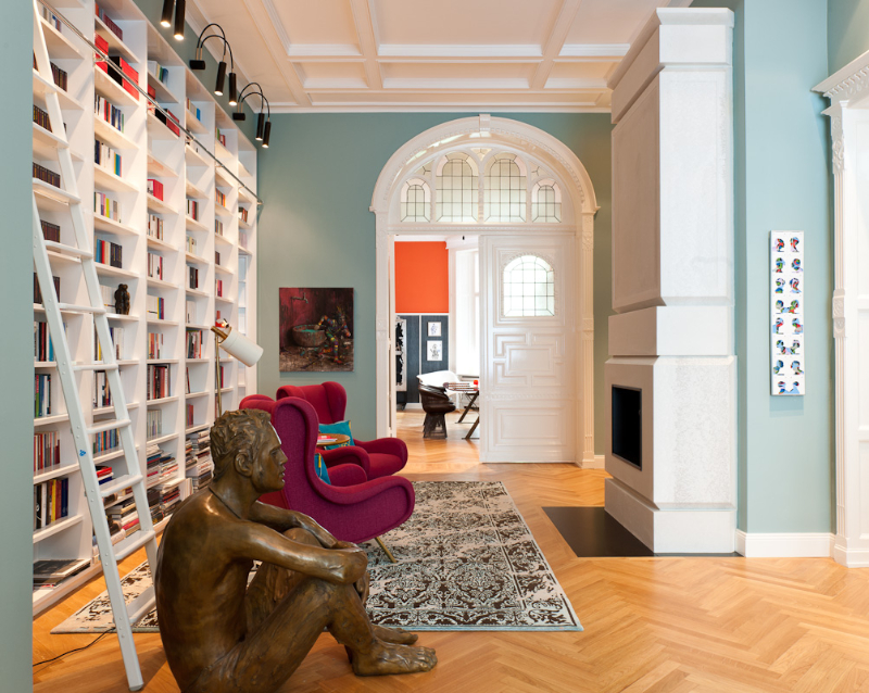 Gisbert Pöppler, The Art of Viewing librabry with blue walls, a rug, a statue and 2 pinkish armchairs