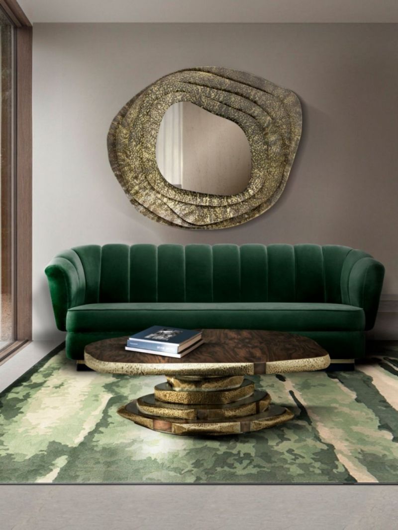 living room by rug'society with green sofa, green rug, brown and golden coffee table, golden wall mirror