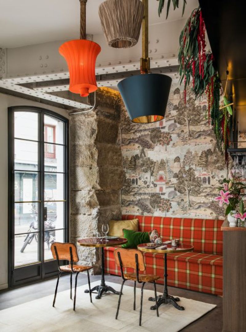 Restaurant by Ines benavides with red sofa and wooden chairs, colomful suspension lamps, white rug
