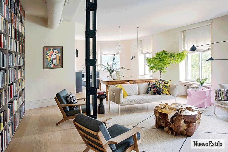 living room by ines benavides with grey amrchairs, white sofa, white rug and floor to ceiling library