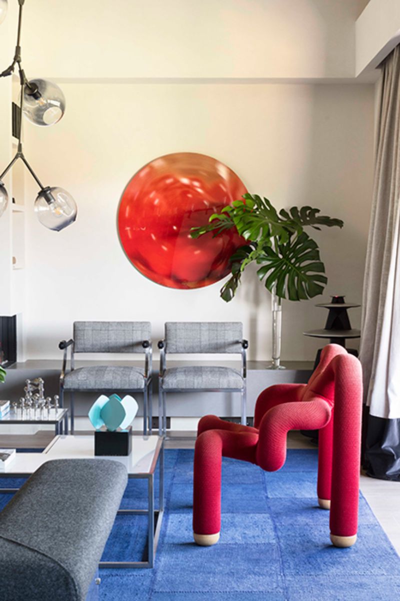 living room by ines benavides with irregular fucsia chair, grey chairs and sofa, white coffee table and blue rug