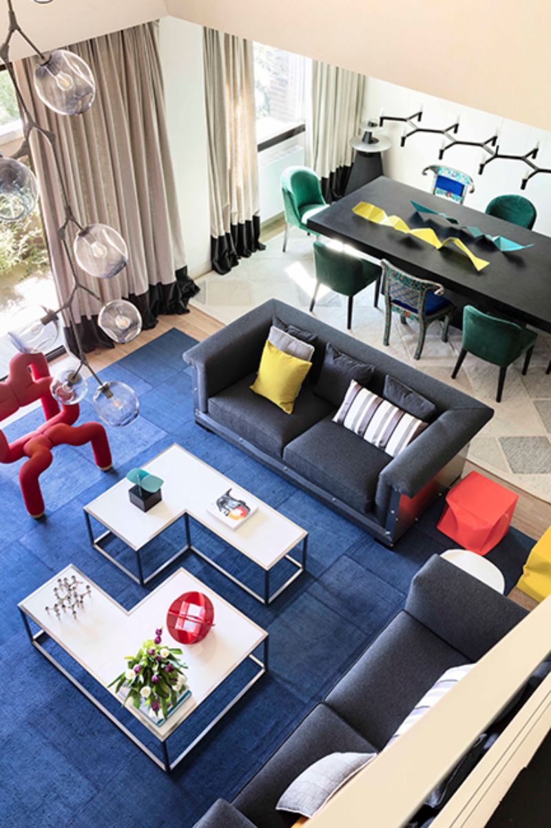 living room by ines benavides with irregular fucsia chair, grey chairs and black sofa, white coffee table and blue rug