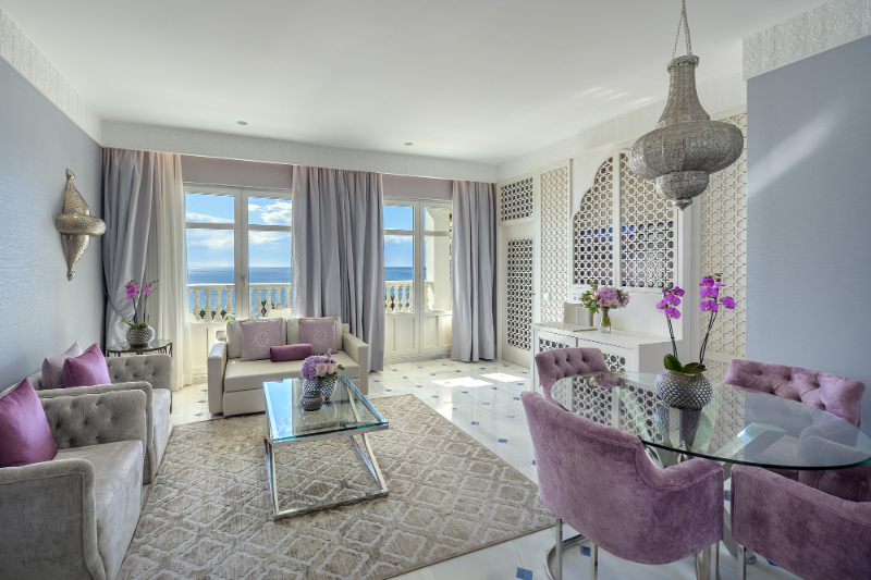 Living room by Aneta Mijatovic with pink and grey chairs, beige rug