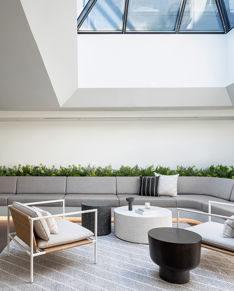 Rug designs from Mason Studio. This living room has a grey sofa, two grey armchairs and three coffe tables in white and black and a big rug in grey with white lines.