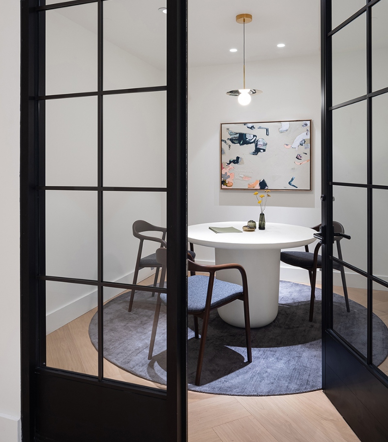 Rug designs from Mason Studio. This smal dining room has a round white teble, threee blue armchairs with wood strcuture and a round blue rug.