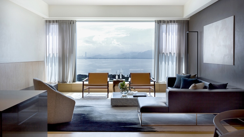 Rug designs from Mason Studio. This living room has a grey wall and all the others are white, a grey sofa, two chairs in yellow and one armchair in white and, a blue and white rug.