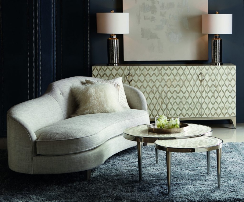Rug Décor with Import Temptations. This seating area with dark blue walls has a neutral console, a neutral sofa, a gold coffee table, and a blue rug.