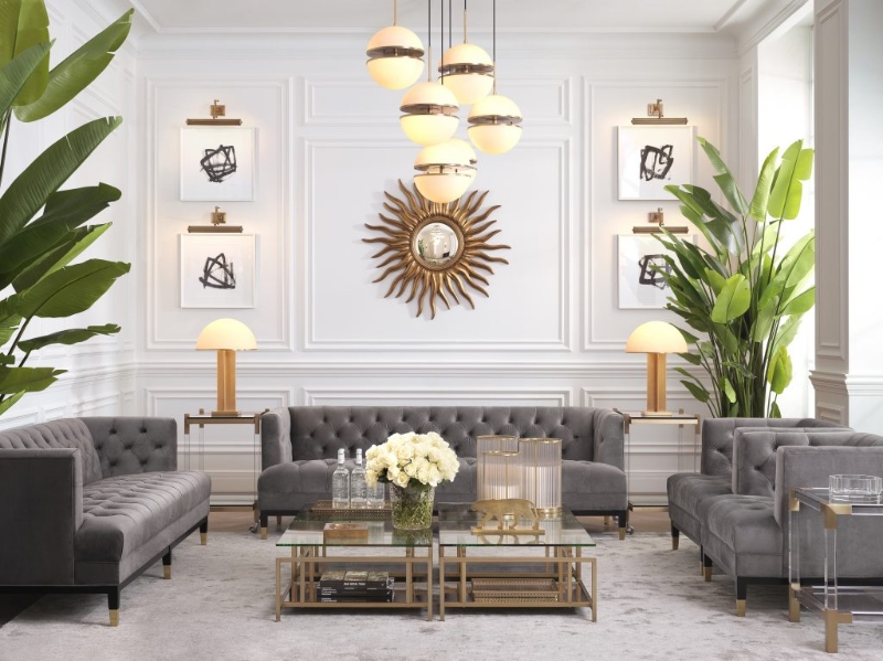 Rug Décor with Import Temptations. This modern living room has a suspension chandelier, two greys sofas, two grey armchairs, a glass coffee table, and a light grey rug.