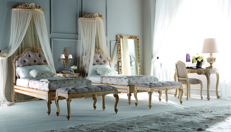Rug Décor with Import Temptations. This luxurious bedroom has two beds with pink bed frames, two grey benches in grey, a vanity table and a pink armchair, and a grey light rug.