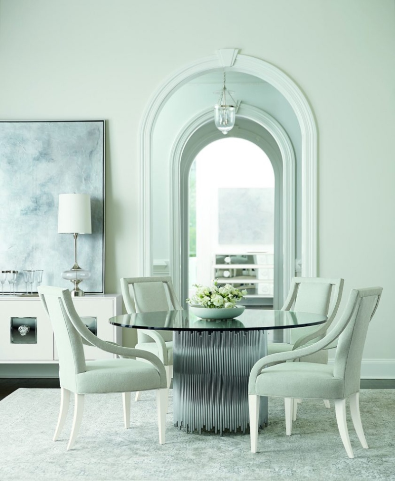 Rug Décor with Import Temptations. This white dining room has a glass dining table, white dining armchairs, and a white rug.