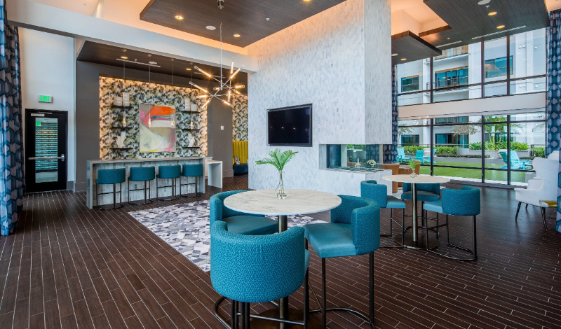 Rug Design Inspiration From Faulkner Design Group. A bar area with blue bar chairs. There's a big rug that gives a cozier ambience to the room.