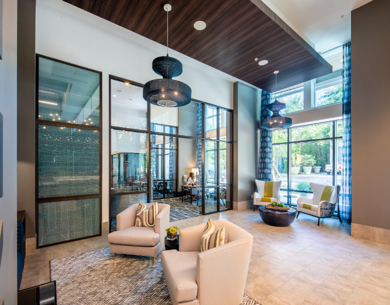 Rug Design Inspiration From Faulkner Design Group. A living area with two light-colored single sofas on a black and white rug, and two armchairs on the corner.