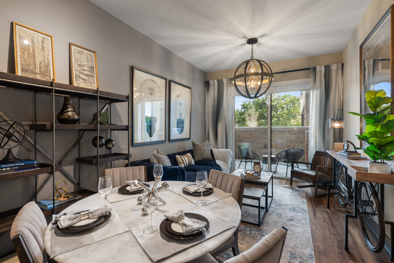 Rug Design Inspiration From Faulkner Design Group. A living and dinning room sharing the same space. There's a 3 seat blue sofa and a round dining table for 4 people sharing the same wide rug.