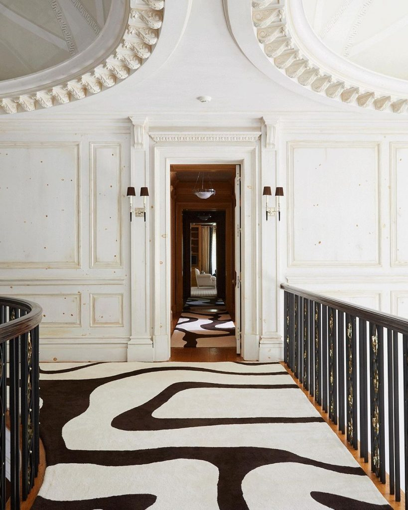 Unique hallway design with neutral colors and black and white rug