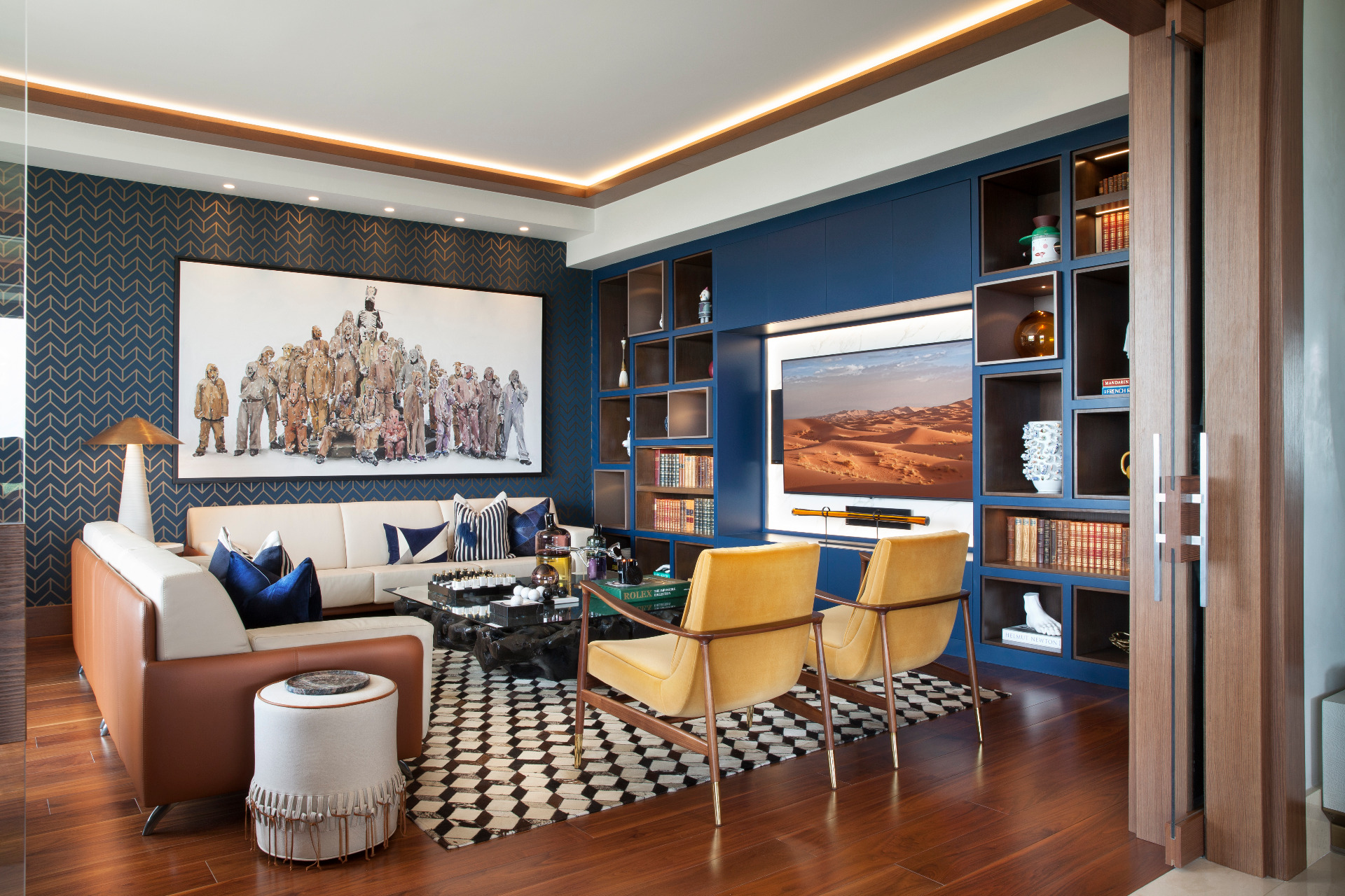 Mid-century living room with black and white rug, yellow armchairs and blue walls.