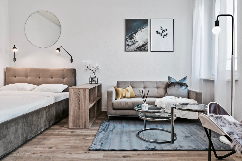 friedenstraße - berlin friedrichshain bedroom with a blue rug and a brown couch, and 3 glass center tables.