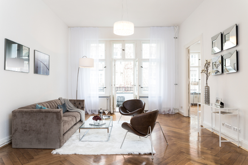 erlesener jugendstil altbau - berlin schöneberg other view of the living room with the white rug, a brown sofa and 2 brown armchairs.