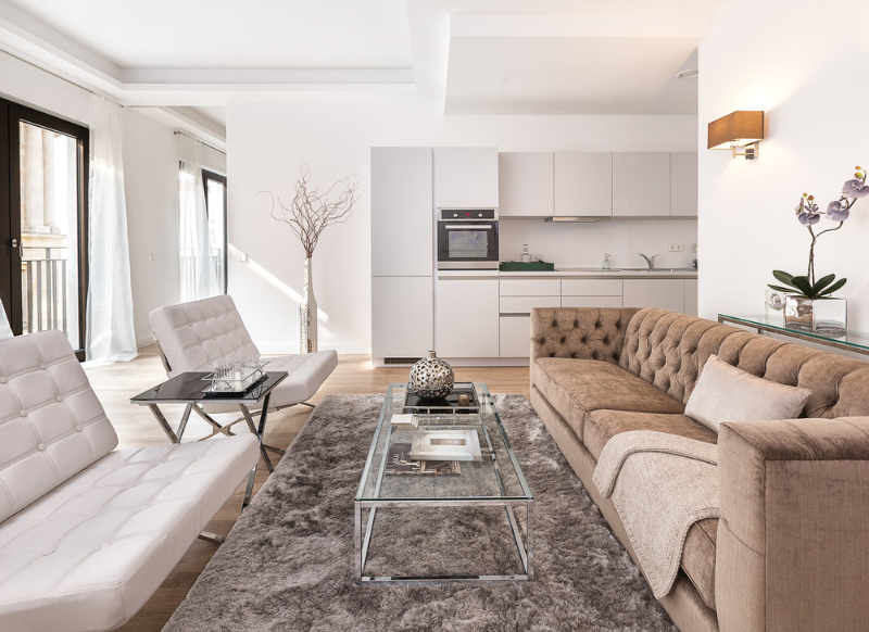 palais theising - berlin gendarmenmarkt living room with a brwon shaggy rug, a light brown sofa, and 2 white sofas with a square glass center table in the middle.