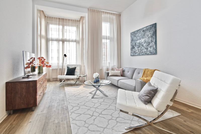 repräsentative musterwohnung - berlin friedrichshain living room with a cell like white rug, 2 white amchars, one grey sofa with a glass center table.