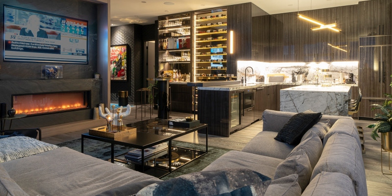 Rug ideas with Navigate Design. This master ensuite in open space has a grey sofa, a blue rug, and a kitchen with marble countertops.