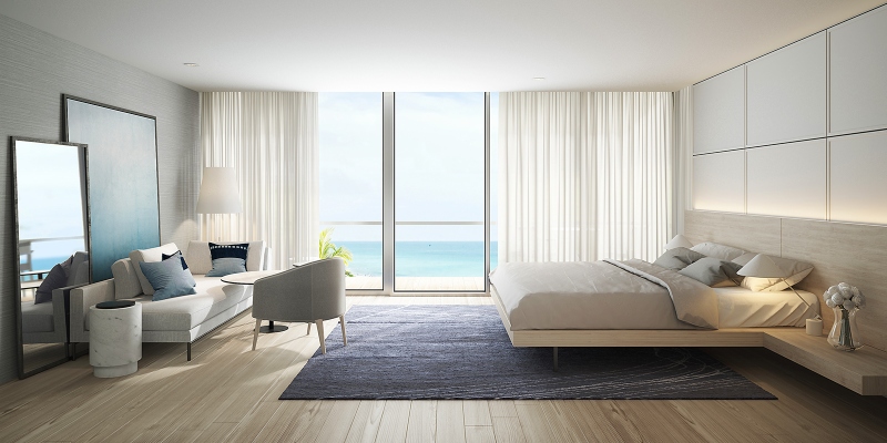 Rug ideas with Navigate Design. This white modern bedroom has a bed frame in light wood. a blue rug, a white lounge, and one grey armchair.