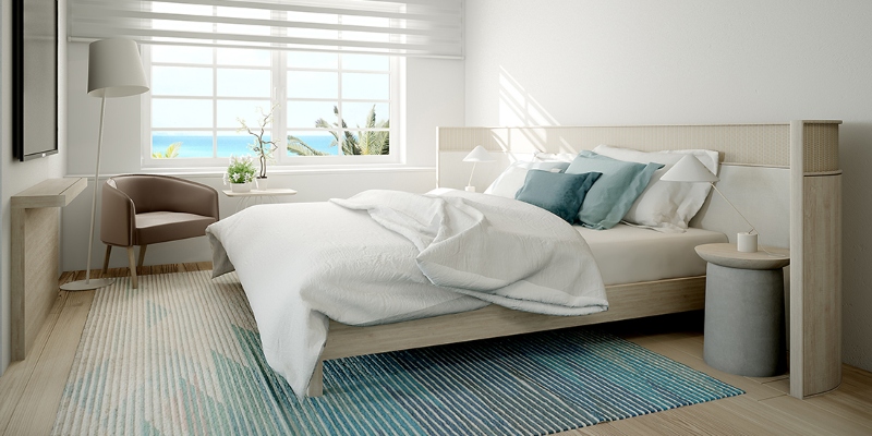Rug ideas with Navigate Design. This neutral living room has a white bed frame, a bedside table in white, a blue and white rug, and a brown armchair.