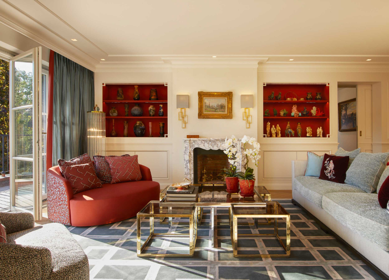 Raumkonzepte Peter Buchberger, Villa Bogenhausen living room with a square patterned rug, a golden center table, a red single sofa, a light grey sofa ad a fireplace
