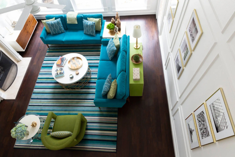 Rug Design Inspiration by Karen Davis. This is a colorful living room with blue and green sofas matching the striped rug.