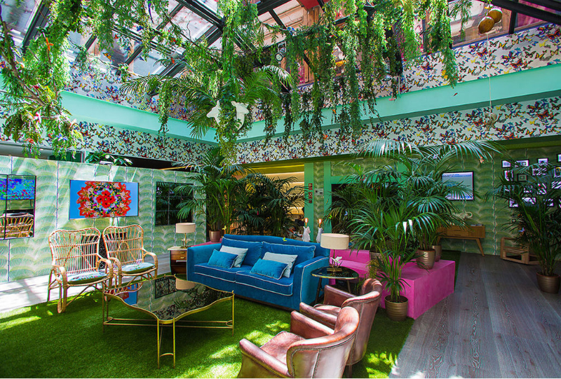 living room by Guille García Hoz with green carpet, glass center table, blue sofa, plants and leather armchairs